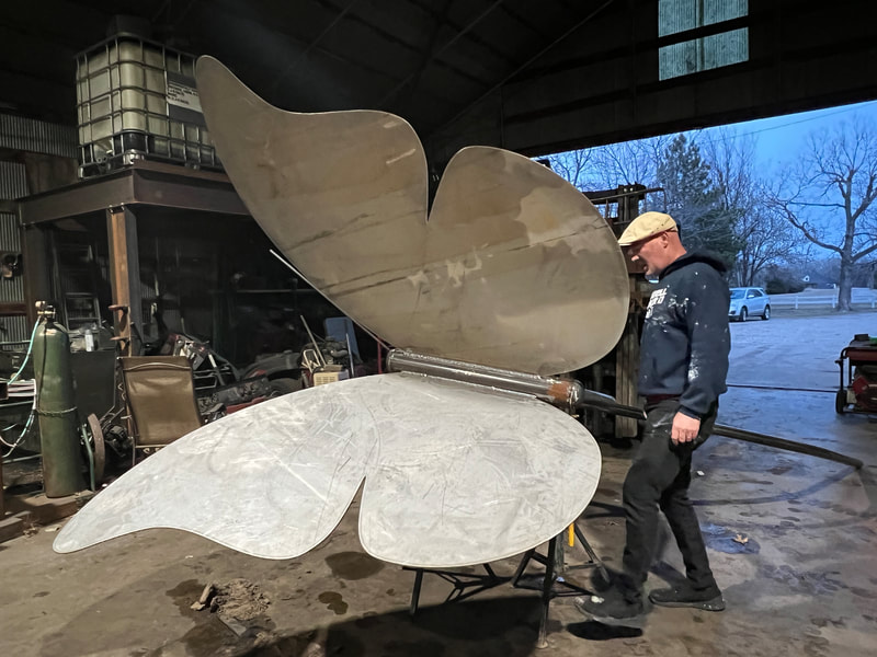 giant metal butterfly with Ty standing next to it, in progress