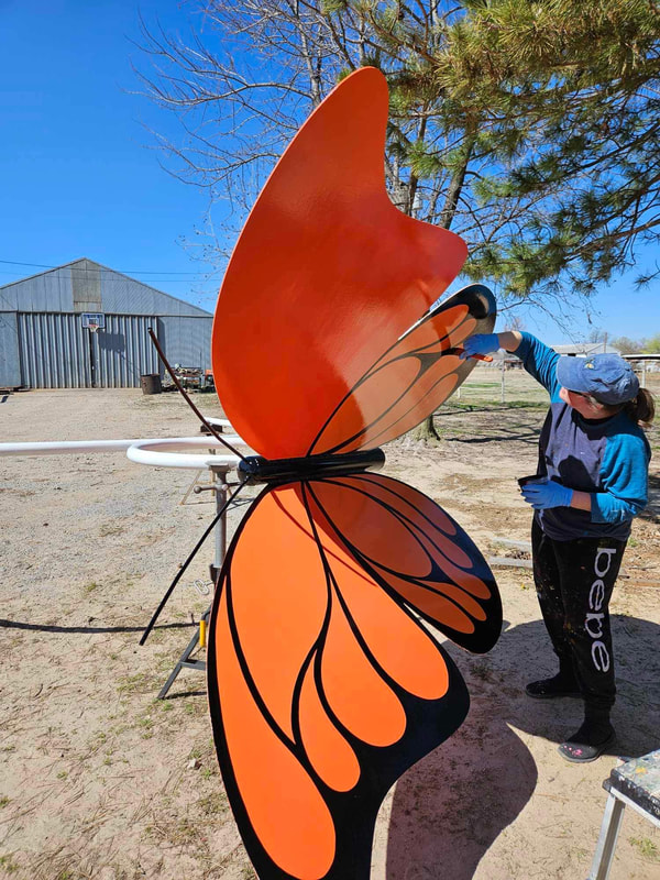 Kelly painting black lines on the giant metal butterfly