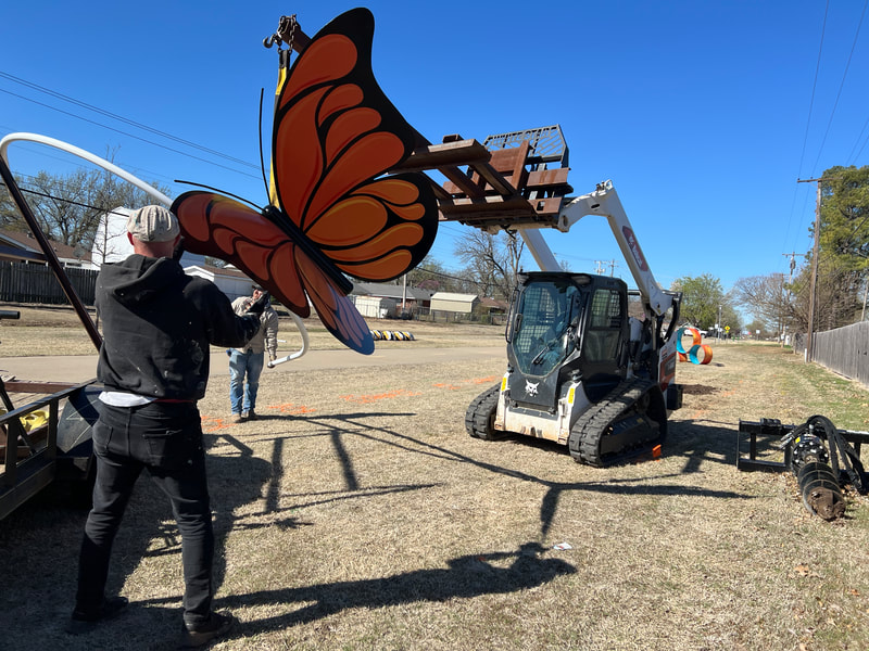 lifting the metal butterfly sculpture off the trailer