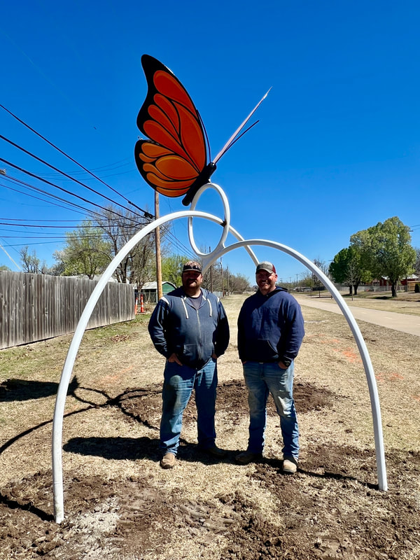 Derick Spencer and Wesley Spencer standing under the nearly finished butterfly sculpture